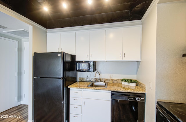 kitchen featuring black appliances, a sink, wood finished floors, white cabinets, and light stone countertops