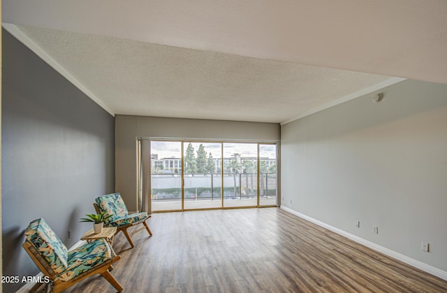 unfurnished room with a textured ceiling, crown molding, baseboards, and wood finished floors