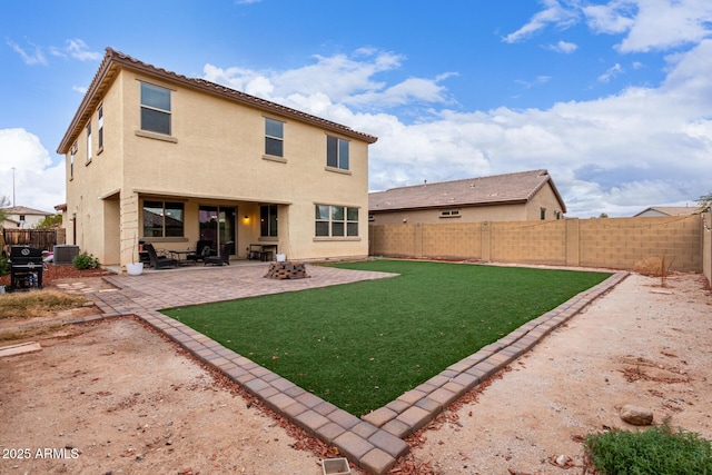 rear view of house with a fire pit, a yard, central AC, and a patio area