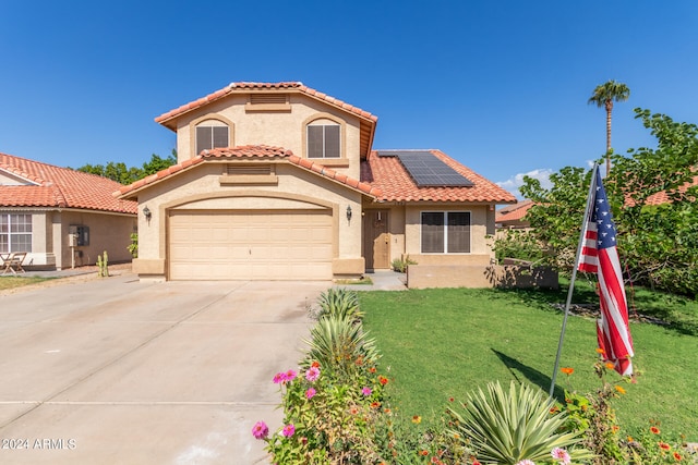 mediterranean / spanish-style home featuring a front yard, solar panels, and a garage