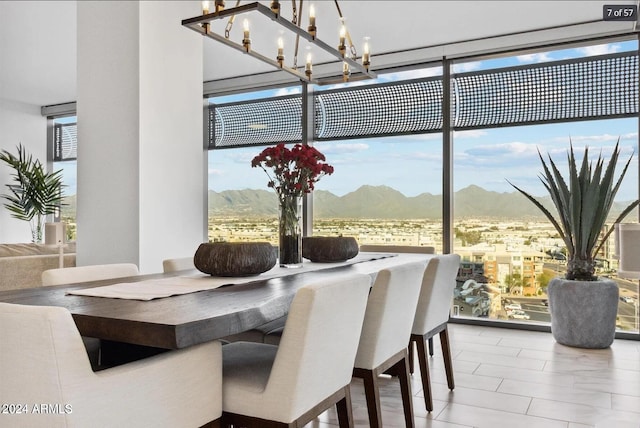 dining space featuring a mountain view, plenty of natural light, an inviting chandelier, and a wall of windows