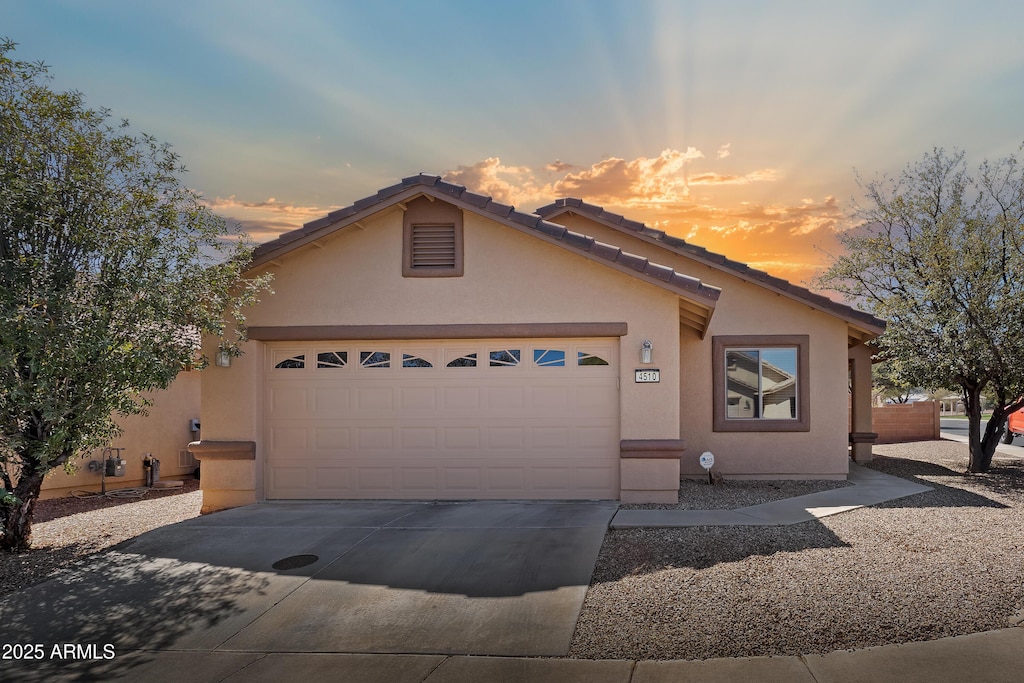 view of front of home with a tiled roof, stucco siding, driveway, and a garage