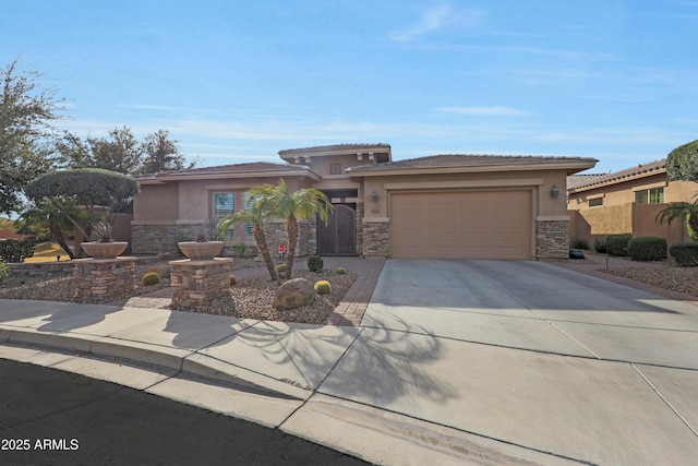 prairie-style home with concrete driveway, stone siding, an attached garage, fence, and stucco siding