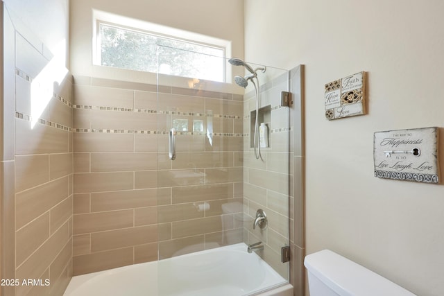 bathroom featuring toilet and bath / shower combo with glass door