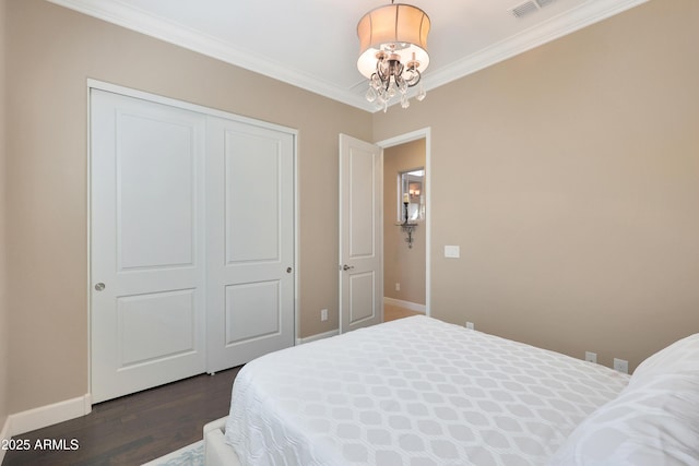 bedroom with baseboards, dark wood-style floors, an inviting chandelier, crown molding, and a closet