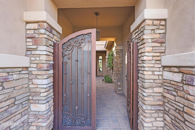 entrance to property with stone siding and a gate