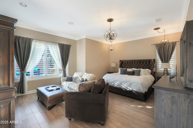 bedroom with an inviting chandelier, wood finished floors, visible vents, and crown molding