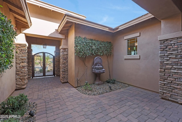 doorway to property featuring stone siding, a gate, and stucco siding