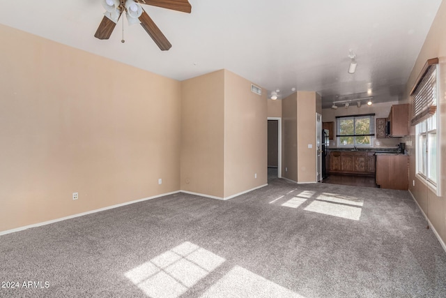 unfurnished living room with ceiling fan, carpet floors, and rail lighting