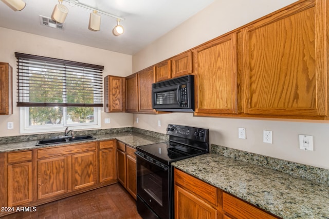 kitchen featuring dark wood-type flooring, track lighting, black appliances, sink, and light stone countertops