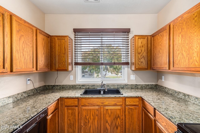 kitchen featuring light stone counters, sink, and black stove