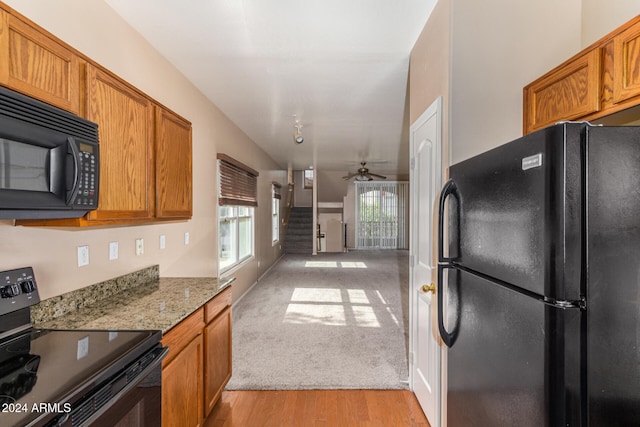 kitchen featuring black appliances, ceiling fan, light hardwood / wood-style floors, and light stone counters