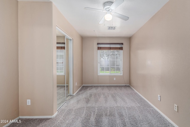 empty room featuring ceiling fan and light carpet