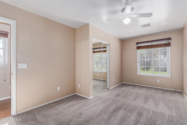 carpeted spare room with ceiling fan and plenty of natural light