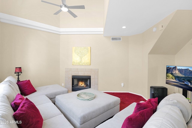 living room featuring a tile fireplace, carpet floors, and ceiling fan