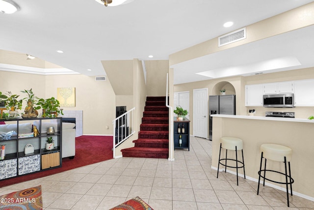 kitchen with white cabinetry, stainless steel appliances, a breakfast bar, and light tile patterned flooring