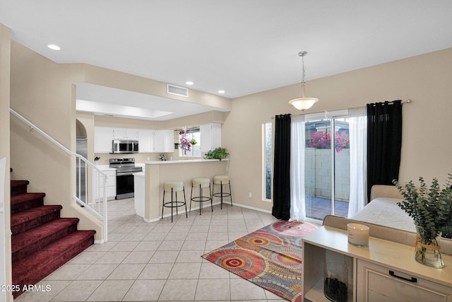 kitchen featuring a breakfast bar area, appliances with stainless steel finishes, kitchen peninsula, pendant lighting, and white cabinets