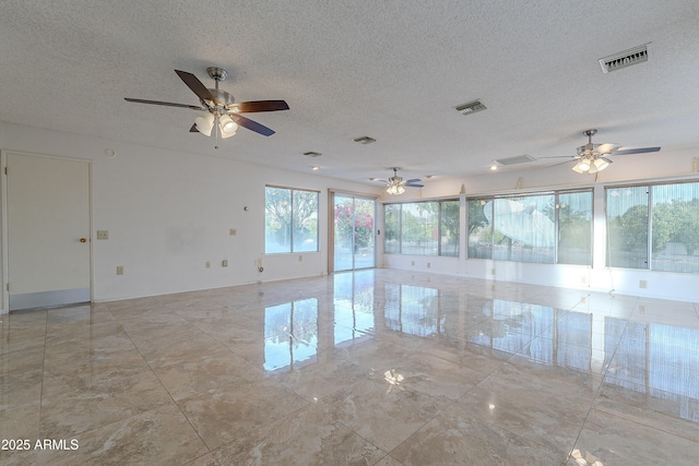 unfurnished room with a textured ceiling, plenty of natural light, and ceiling fan