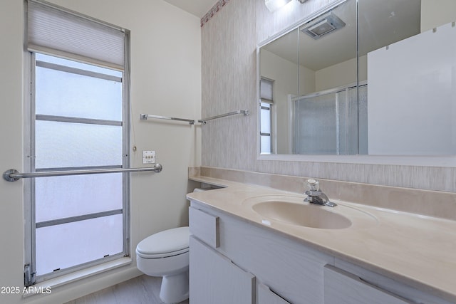 bathroom with vanity, toilet, a shower with door, and a wealth of natural light