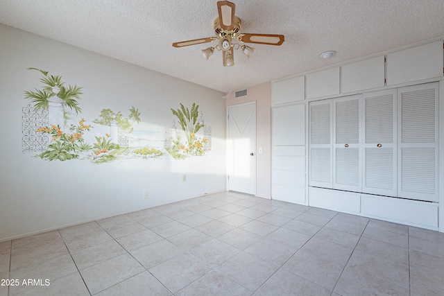 unfurnished bedroom featuring light tile patterned floors, a textured ceiling, a closet, and ceiling fan