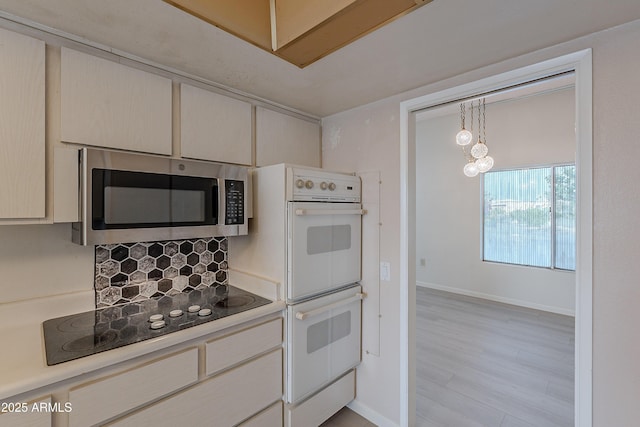 kitchen with an inviting chandelier, double oven, cream cabinetry, black electric stovetop, and light wood-type flooring