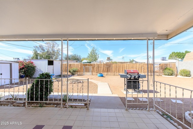 view of patio featuring a storage unit, grilling area, fence, and an outdoor structure