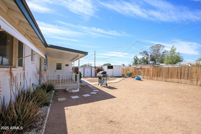 view of yard featuring fence, a storage unit, a patio, and an outbuilding