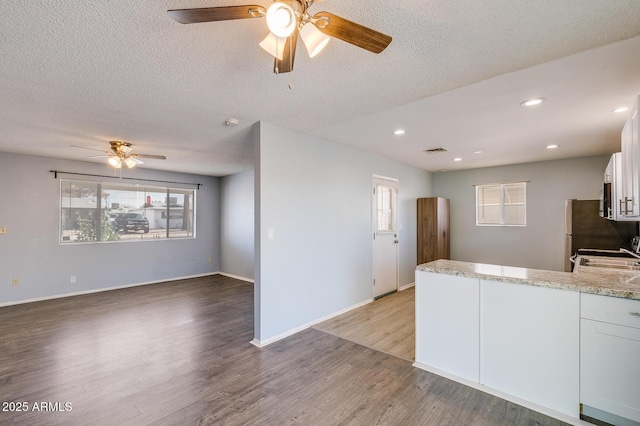 kitchen featuring white cabinets, light wood-style flooring, a peninsula, and light stone countertops