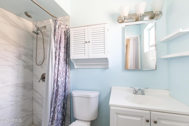 bathroom with tiled shower, vanity, and toilet