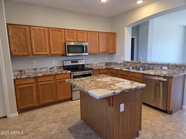 14621 W Catalina Dr, Goodyear, AZ 85395 - kitchen with appliances with stainless steel finishes, brown cabinets, light stone counters, recessed lighting, and a kitchen breakfast bar