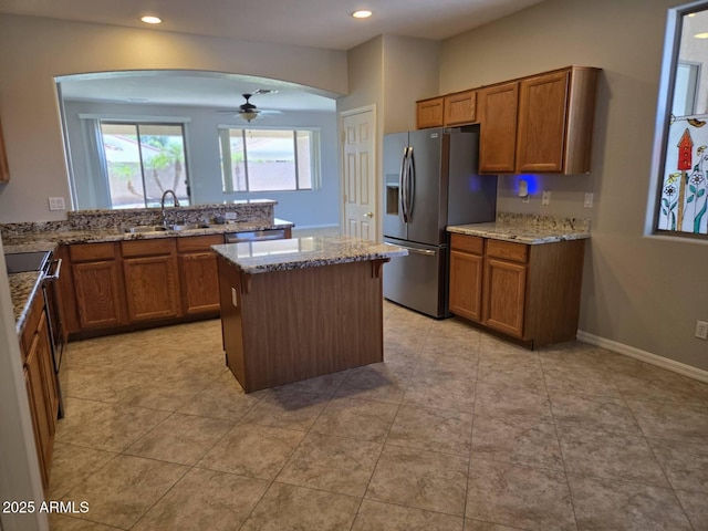 14621 W Catalina Dr, Goodyear, AZ 85395 - kitchen featuring appliances with stainless steel finishes, brown cabinetry, ceiling fan, a center island, and recessed lighting