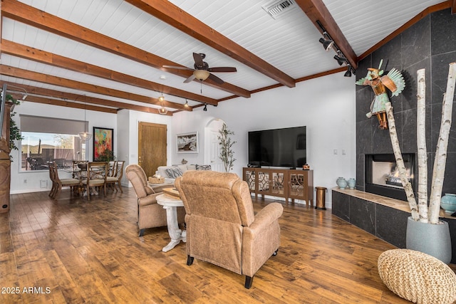 living area featuring a large fireplace, visible vents, wood finished floors, and beamed ceiling