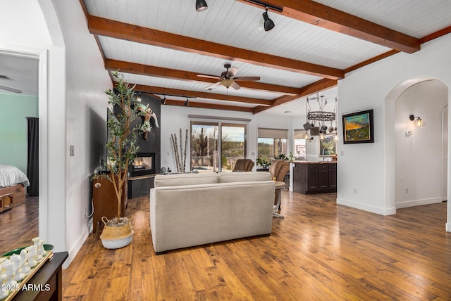 living room with arched walkways, baseboards, a multi sided fireplace, and wood finished floors