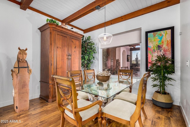 dining area featuring arched walkways, baseboards, beam ceiling, and light wood-style floors