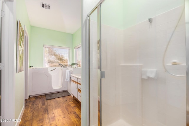 bathroom with wood finished floors, a stall shower, vanity, and visible vents