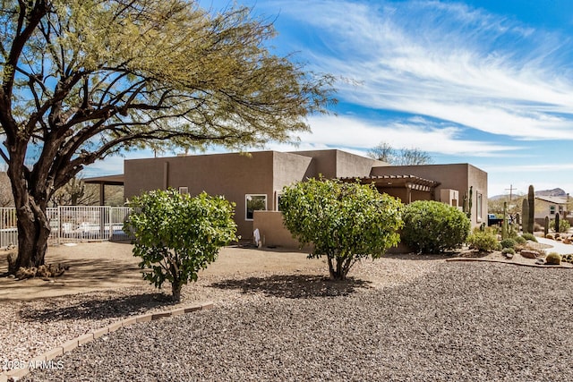 exterior space featuring a pergola, fence, and stucco siding