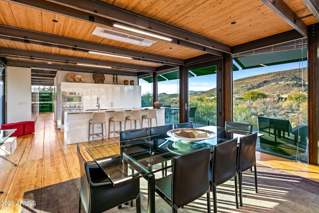 dining area with beam ceiling, wooden ceiling, visible vents, and hardwood / wood-style floors