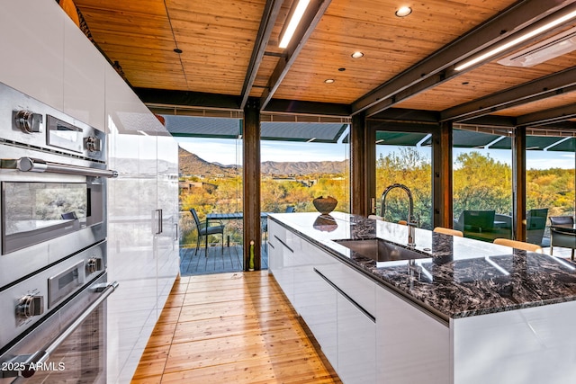 kitchen featuring modern cabinets, white cabinetry, a sink, and oven