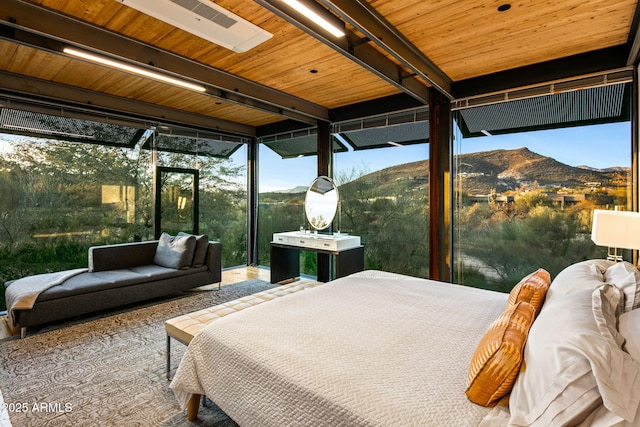 bedroom featuring beam ceiling, a mountain view, and a wall of windows