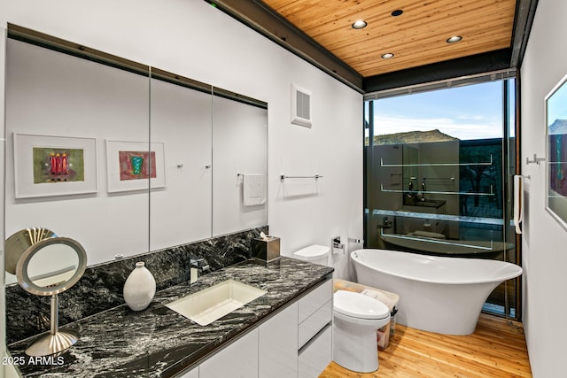 full bath featuring wood finished floors, wood ceiling, vanity, a freestanding bath, and visible vents