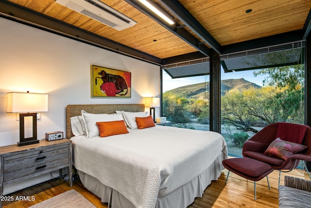 bedroom featuring a mountain view, expansive windows, wood-type flooring, and wooden ceiling