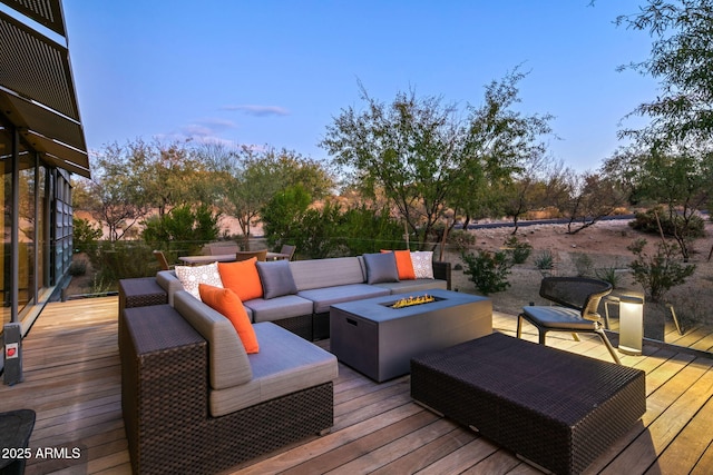 deck at dusk with an outdoor living space with a fire pit