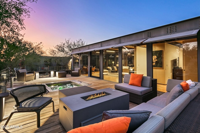 patio terrace at dusk featuring a deck and an outdoor living space with a fire pit