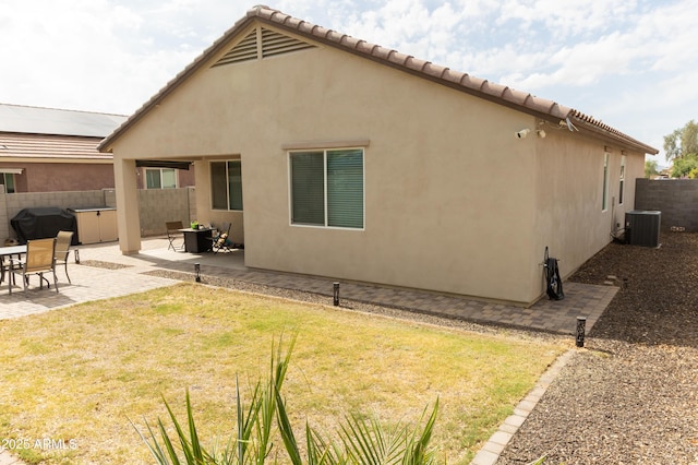 back of property featuring a yard, fence, a patio, stucco siding, and central AC unit