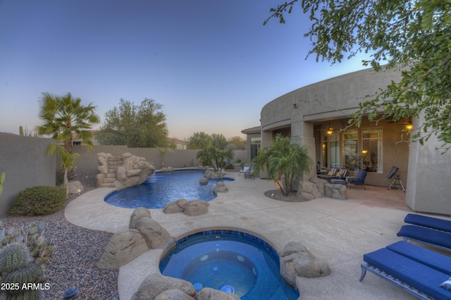 pool at dusk featuring a fenced in pool, an in ground hot tub, fence private yard, and a patio