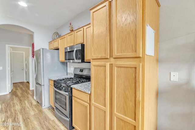 kitchen featuring light brown cabinetry, light stone counters, light hardwood / wood-style floors, and appliances with stainless steel finishes