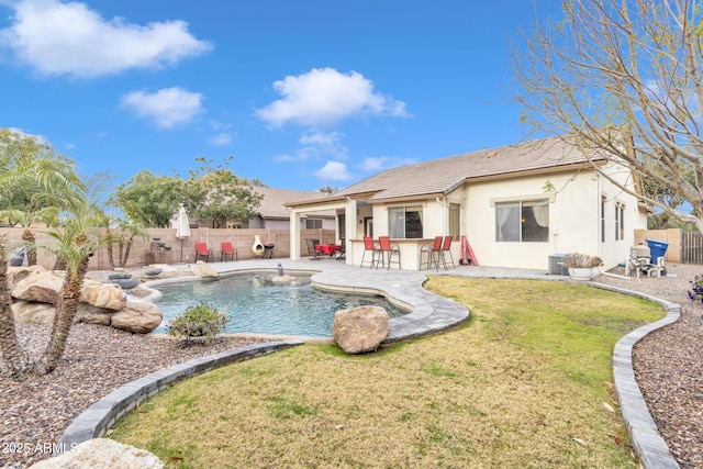 rear view of property with a fenced in pool, a patio, exterior bar, and a yard