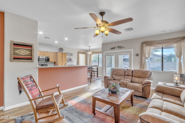 living room featuring light hardwood / wood-style flooring, ceiling fan, and plenty of natural light