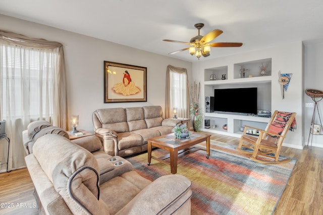 living room with ceiling fan, built in features, and light wood-type flooring