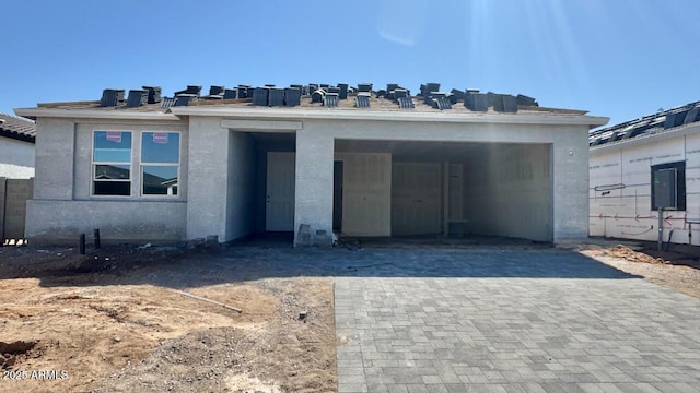 property under construction with stucco siding and decorative driveway